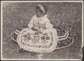 cca 1960 Kalocsavidéki gyermek ünneplőben, hátulján magyarul és németül feliratozva, kisebb szakadásokkal, 22×15,5 cm; valamint a róla készült képeslap (14×9 cm)